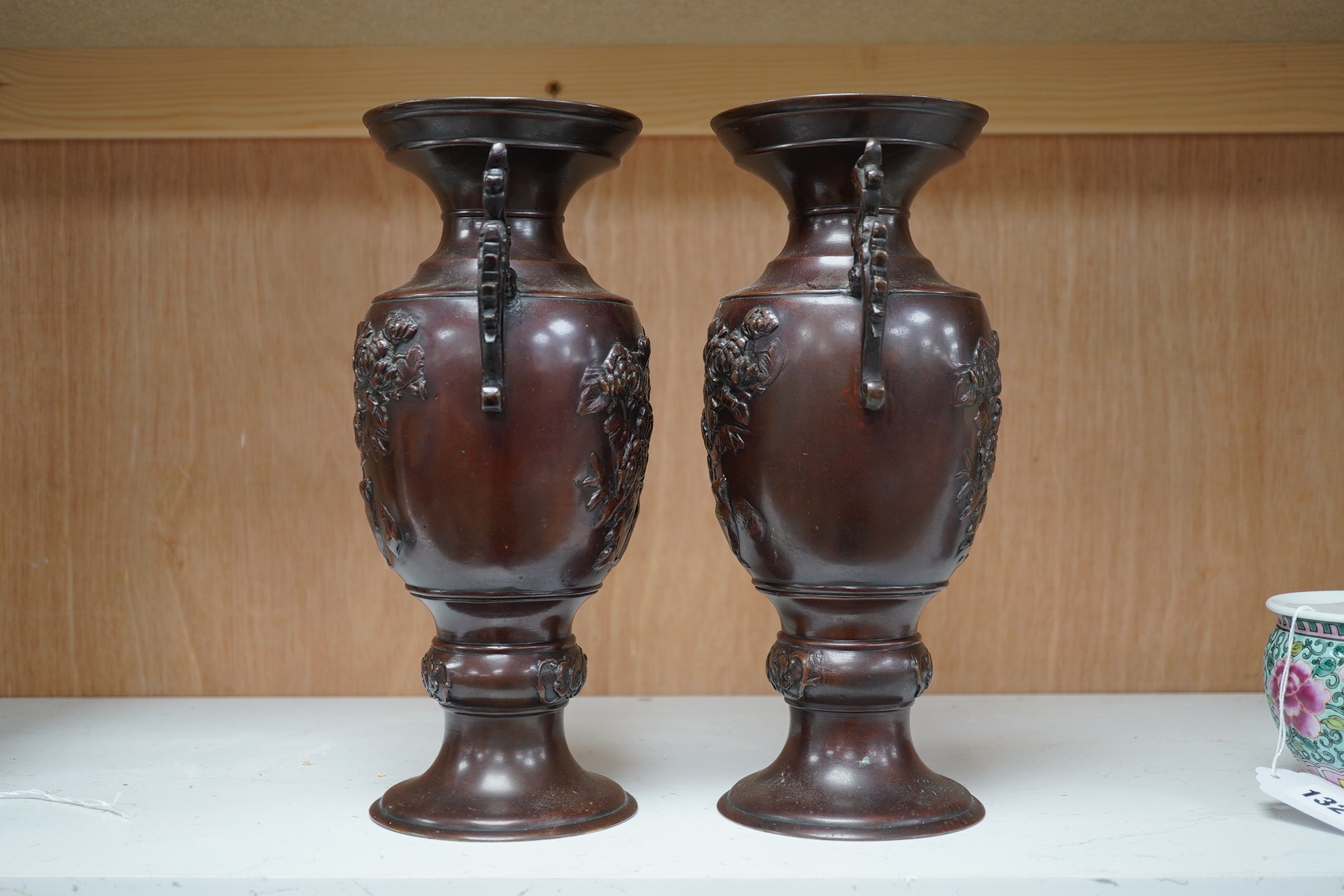 A pair of Japanese two handled bronze vases decorated in relief with birds and flowers, 26cm high. Condition - good